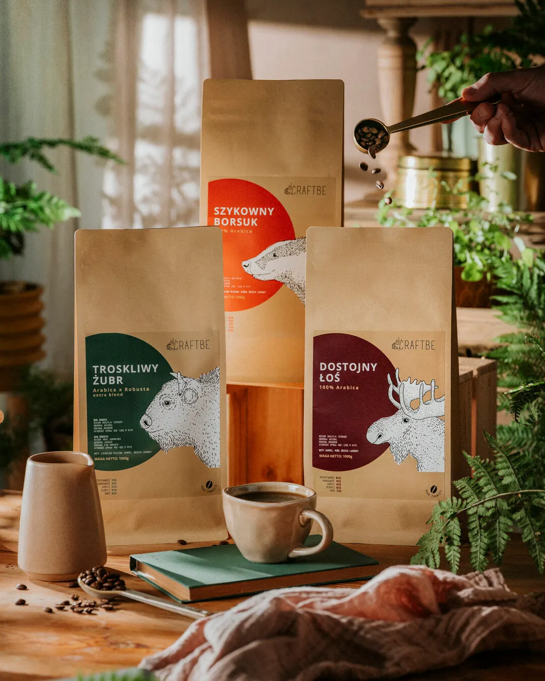 Trzy paczki 1 kg, Troskliwy Żubr, Szykowny Borsuk i Dostojny Łoś, ręka sypie ziarna mosiężną miarką
